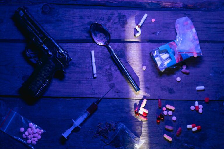 Intriguing still life image depicting pills, a gun, and syringe under dramatic lighting.